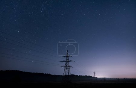 Foto de Torres de transmisión de electricidad con cables brillantes contra el cielo estrellado. - Imagen libre de derechos