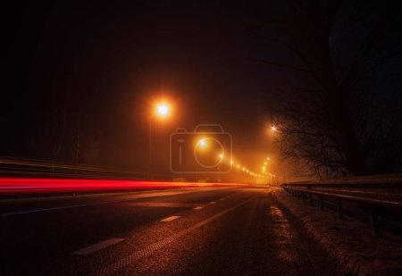 Téléchargez les photos : Autoroute vide avec des sentiers lumineux à partir de la voiture de passage la nuit. - en image libre de droit