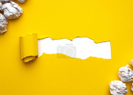 Papier jaune déchiré avec des boules de papier froissées blanches sur fond blanc. Espace pour le texte.