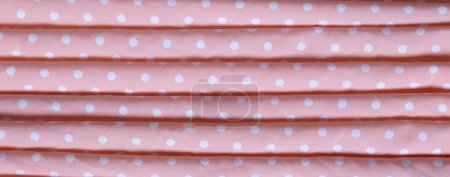 Texture of pink fabric with white dots. Crumpled fabric. Top view.