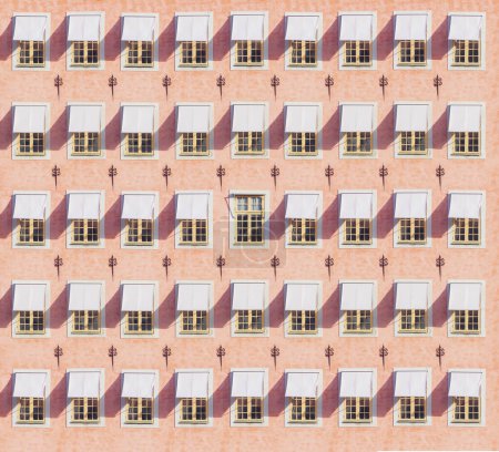 Façade rose du bâtiment. Vieilles fenêtres avec visières. Style rétro. Minimalisme. Concept d'être unique.