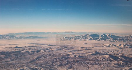 The sky with clouds and mountains in snow. Photo taken from an airplane.