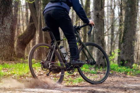 Cyclist on a gravel bike. A cyclist rides along a forest path drifting with the rear wheel and raising the pitch. Active sport concept.