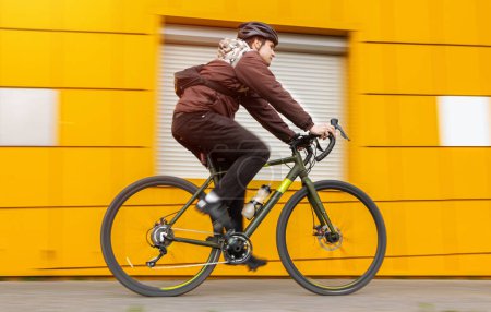 A guy on a gravel bike rides past a yellow wall. Motion blur effect. Active sport concept.