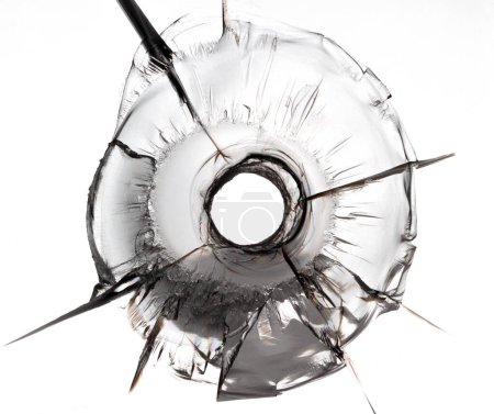 Isolated bullet hole on glass. Cracked glass texture on white background.