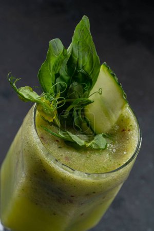 batido verde en un vaso sobre un fondo negro con hielo de manzana de apio de espinacas de pepino para menú de cócteles de restaurante de verano