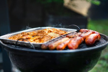 Photo for Summer barbecue in the garden. Shot on a hot grill with meat and sausages. - Royalty Free Image