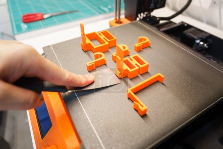 Téléchargez les photos : Une imprimante 3D. Une usine. Suppression d'objets de la table d'impression. - en image libre de droit