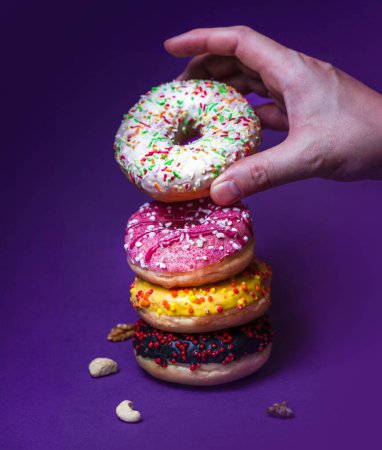 Téléchargez les photos : Un donut à la main. Saupoudrer coloré. Fond pastel. - en image libre de droit