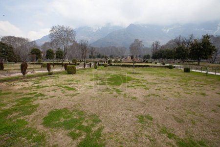 A park in Srinagar, with bushes, trails and a large mountain range in the background.