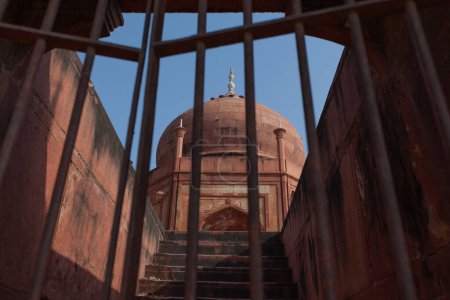 The dome is made of orange stone in India. Taken from behind a window with iron bars.