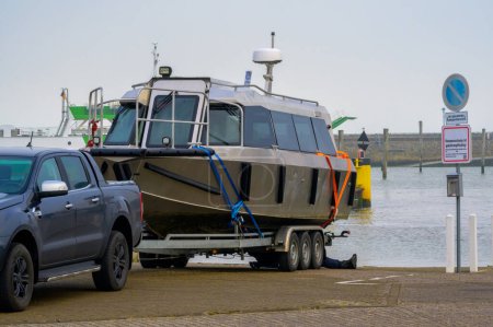 Photo for A high speed water taxi is loaded onto a boat trailer at the end of season in the harbor of Neuharlingersiel, Germany as winter starts - Royalty Free Image