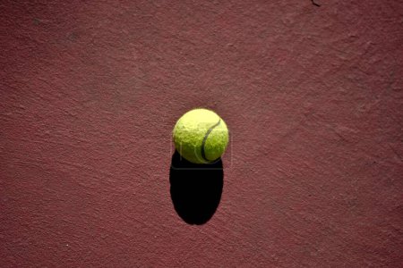 Photo for Tennis ball with black shadow on red court - Royalty Free Image