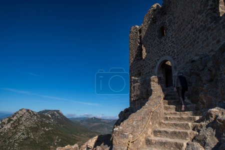 Tourist in the ruins of the medieval castle of Quribus, in the Cathar region of southern France