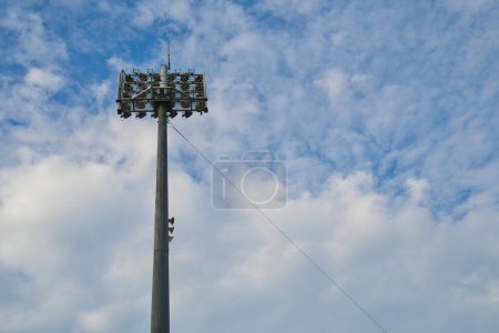 Téléchargez les photos : Un seul pôle de projecteur de stade avec ciel bleu et nuages pelucheux en arrière-plan. - en image libre de droit