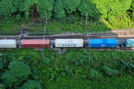 Téléchargez les photos : Kuala Lumpur, Malaisie - 21 décembre 2023 - Cosco expédie des conteneurs à bord d'un train de marchandises par chemin de fer dans une zone forestière. - en image libre de droit
