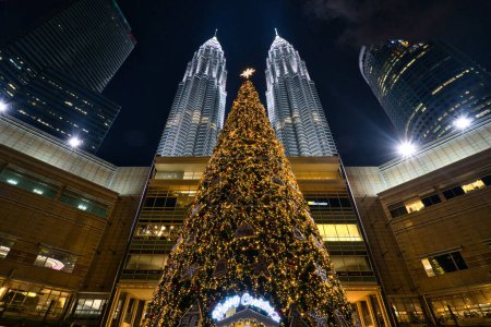 Téléchargez les photos : Kuala Lumpur, Malaisie - 19 décembre 2023 : Arbre de Noël géant allumé au centre commercial Suria KLCC, avec les tours jumelles Petronas en arrière-plan. - en image libre de droit