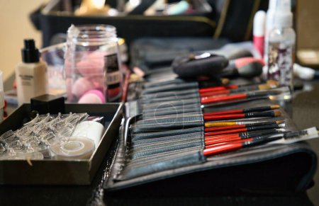 Téléchargez les photos : Cosmétiques décoratifs professionnels, outils de maquillage et accessoires, disposés sur une table. Poste de travail des maquilleurs, bureau, studio. - en image libre de droit