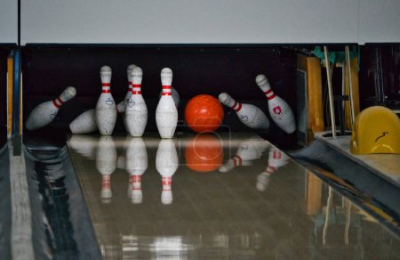 Téléchargez les photos : Balle de bowling orange frappant et renversant broches blanches dans l'allée. Mouvement gelé vif sans flou. - en image libre de droit