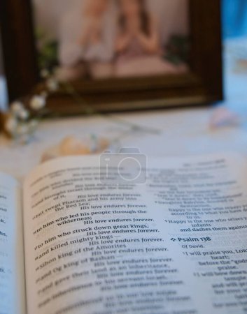 Opened bible on table showing verse on love in Book of Psalms, next to photo of a couple.