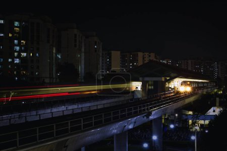 Téléchargez les photos : Voie et gare MRT de Singapour la nuit avec sentier lumineux depuis l'arrivée et le départ du train. Sombre et faible lumière. - en image libre de droit