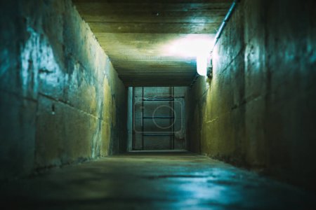 Long tunnel souterrain étroit et sombre dans un vieux bunker, menant à une échelle en acier qui remonte à la surface.