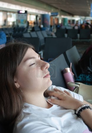 Junge Frau wartet auf ihr Flugzeug, schläft ein wenig im Flughafenterminal