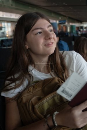 Chica joven en una terminal del aeropuerto internacional esperando a que su avión salga 