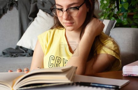 Young woman enjoying reading a book on a quiet afternoon. Study at home concept