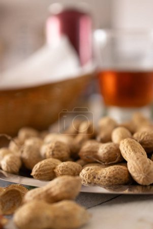 Nahaufnahme von Erdnüssen mit Schalen auf einem Tisch, zubereitet für einen erfrischenden Aperitif