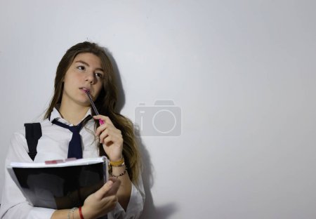Teenagermädchen in Schuluniform mit ihrem Notizbuch und Sorgen um den bevorstehenden Unterricht.