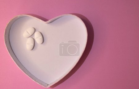Concept of heart care. Graphic resource to promote body care and health.Horizontal top view photo with space for copy on pastel pink background.