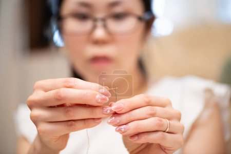 Foto de Una mujer que usa anteojos enhebrando una aguja - Imagen libre de derechos