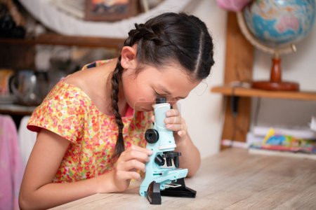 Téléchargez les photos : Fille regardant à travers un microscope - en image libre de droit