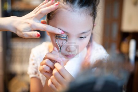 Téléchargez les photos : Fille pratiquant le maquillage tout en regardant dans le miroir - en image libre de droit
