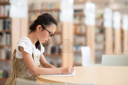 Foto de Chica estudiando en la biblioteca - Imagen libre de derechos