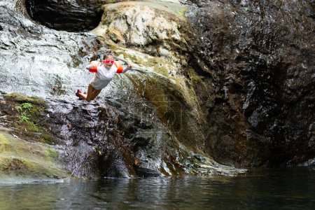 Téléchargez les photos : Un gamin qui saute dans la rivière - en image libre de droit