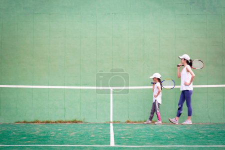Photo for Young girl and mother  playing tennis on court - Royalty Free Image