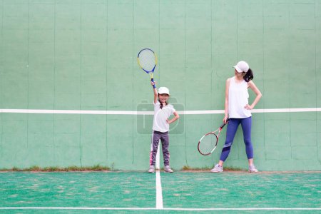 Foto de Young girl and mother  playing tennis on court - Imagen libre de derechos