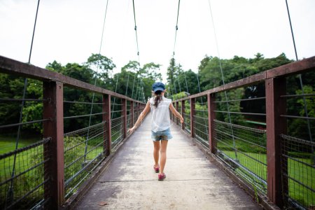 Photo for Girl walking on suspension bridge - Royalty Free Image