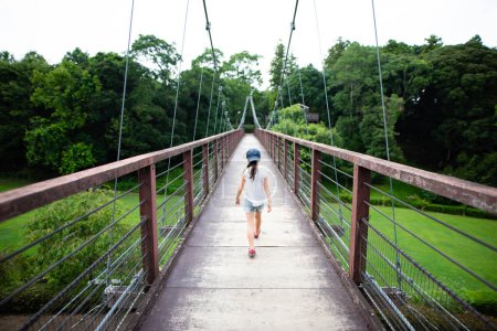 Photo for Girl walking on suspension bridge - Royalty Free Image