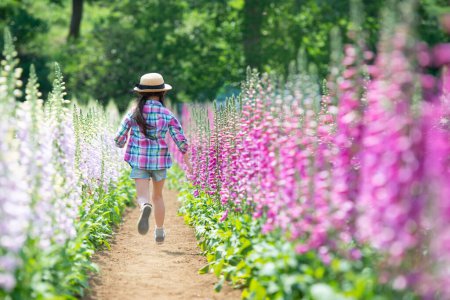 Téléchargez les photos : Fille jouant dans le champ de fleurs - en image libre de droit