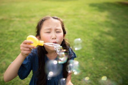 Photo for Young asian girl playing with soap bubbles   in  park - Royalty Free Image