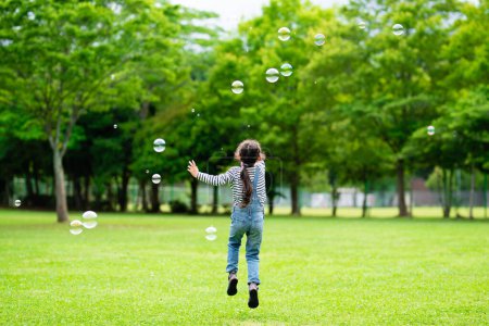 Photo for Asian girl playing with soap bubbles outdoors - Royalty Free Image
