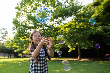 Foto de Joven asiático chica jugando con jabón burbujas en parque - Imagen libre de derechos