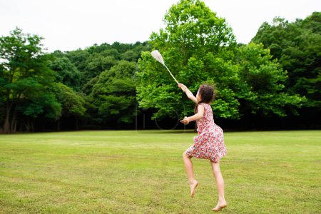 Téléchargez les photos : Une fille jouant pieds nus avec un filet à insectes - en image libre de droit