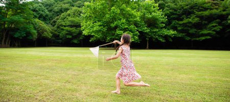 Téléchargez les photos : Une fille jouant pieds nus avec un filet à insectes - en image libre de droit