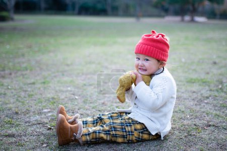 Foto de Little asian girl with teddy bear  in park. - Imagen libre de derechos