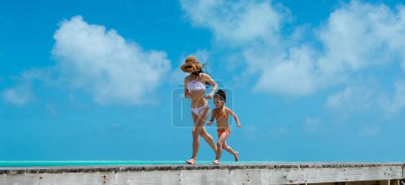 Téléchargez les photos : Mère et fille courant sur la plage - en image libre de droit