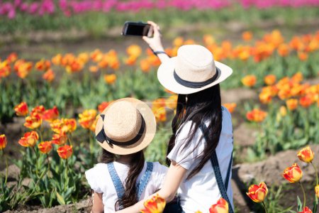 Téléchargez les photos : Mère et fille prenant des photos dans le champ de fleurs - en image libre de droit